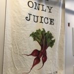 Tapestry with Not Only Juice Restaurant logo. Black font accompanied by a painting of beets.