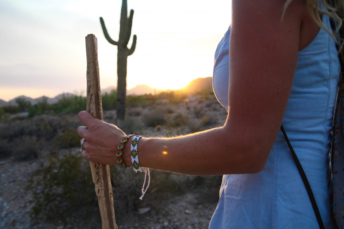 A woman holds a walking stick as she prepares to walk through the desert.